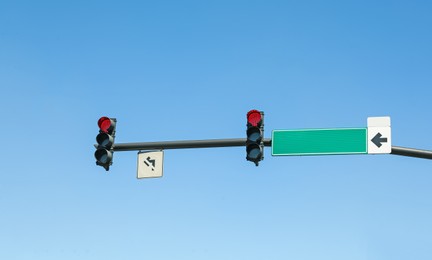 Photo of Traffic lights against blue sky. Road rules