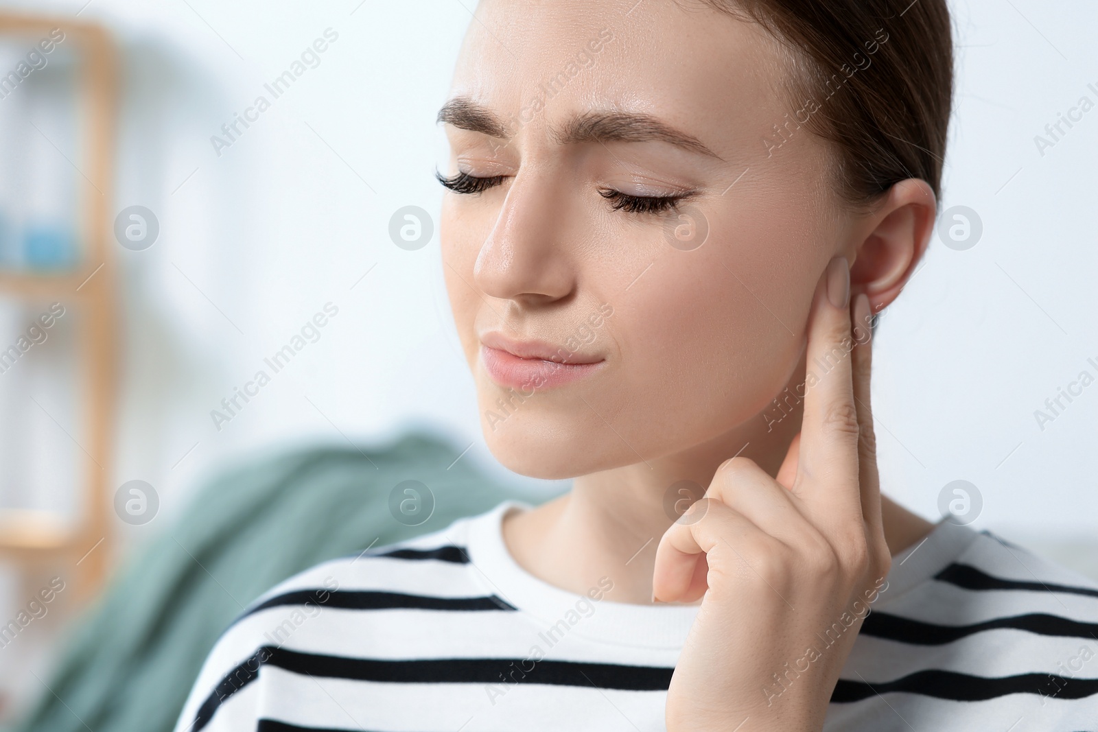 Photo of Young woman suffering from ear pain indoors, closeup