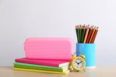 Photo of Different school stationery and alarm clock on table against white background. Back to school