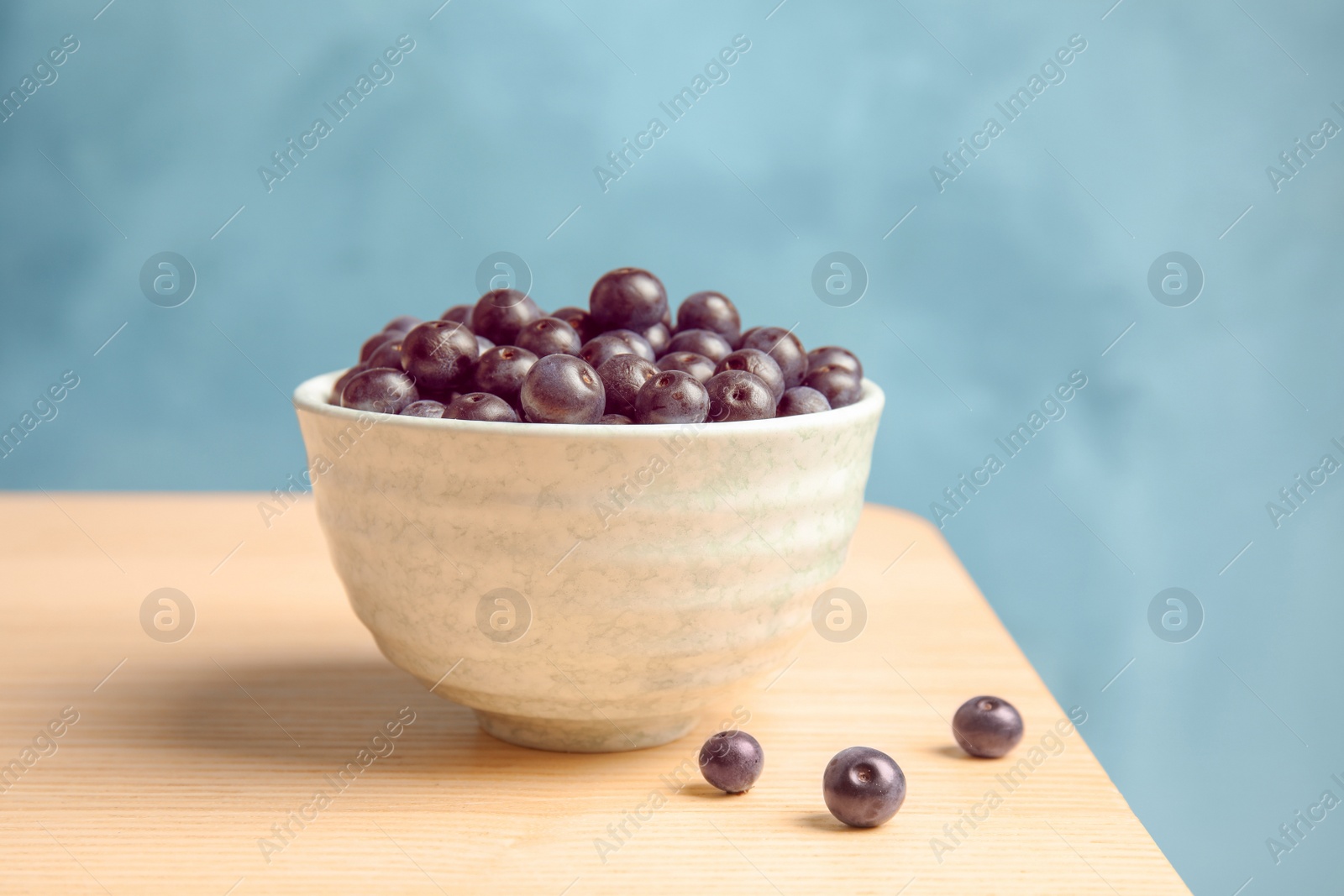 Photo of Bowl with fresh acai berries on table