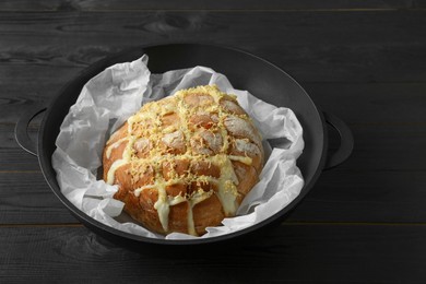 Photo of Freshly baked bread with tofu cheese and lemon zest on black wooden table