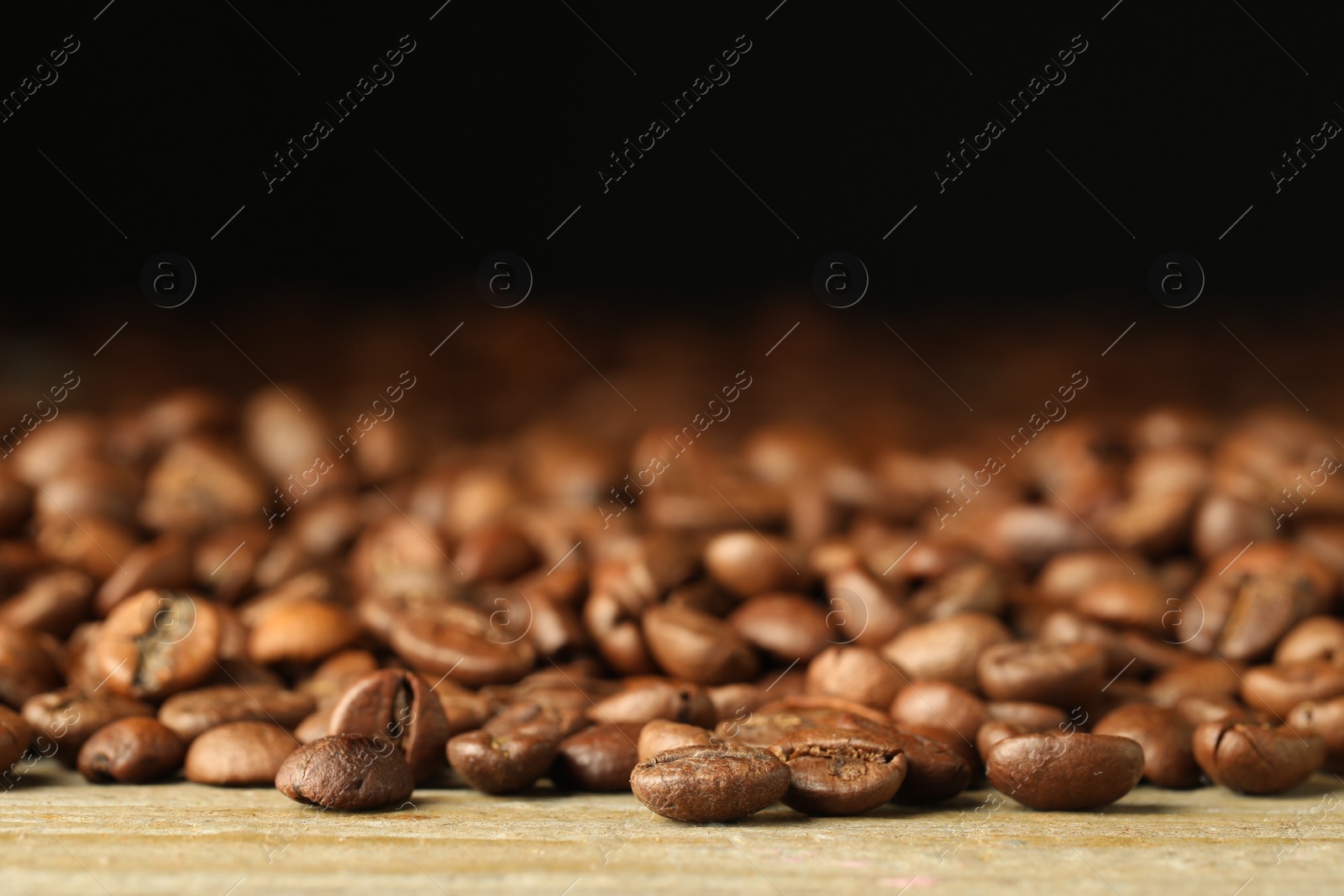 Photo of Many roasted coffee beans on wooden table, closeup