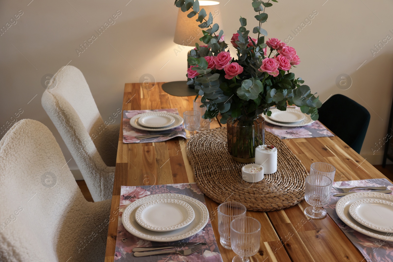 Photo of Beautiful table setting with bouquet and candles indoors. Roses and eucalyptus branches in vase