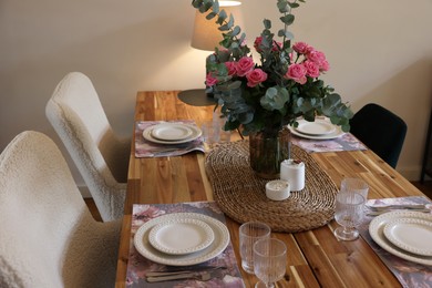 Beautiful table setting with bouquet and candles indoors. Roses and eucalyptus branches in vase