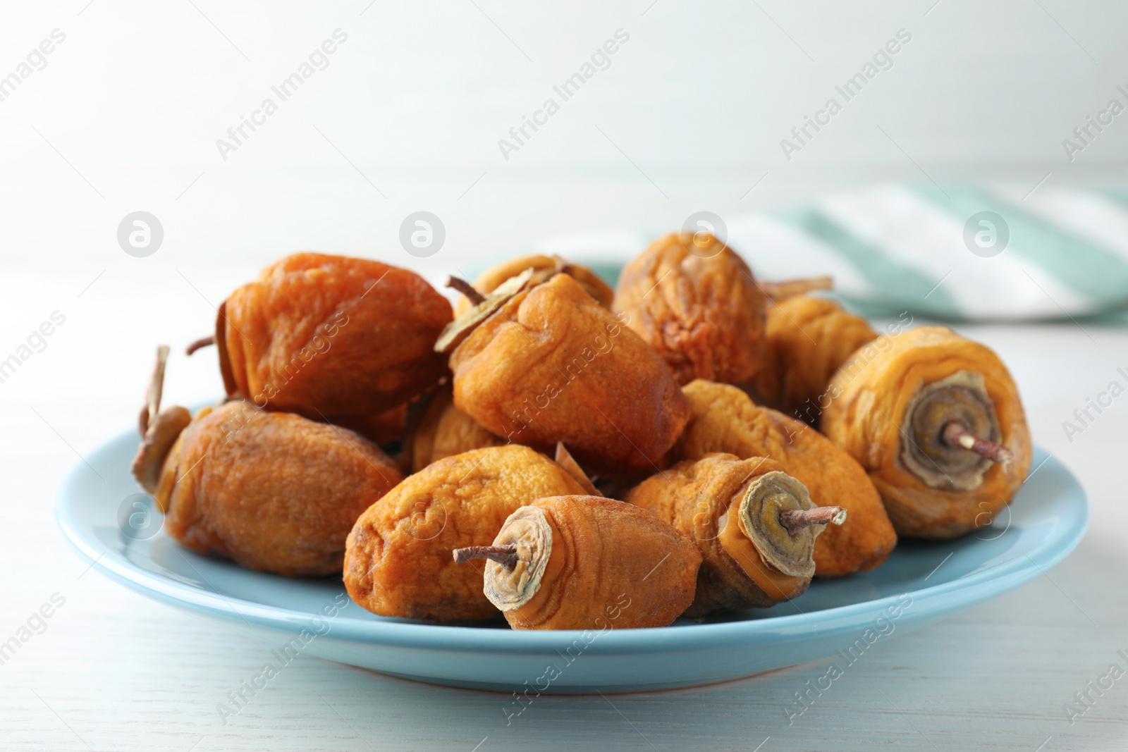 Photo of Plate with tasty dried persimmon fruits on white wooden table