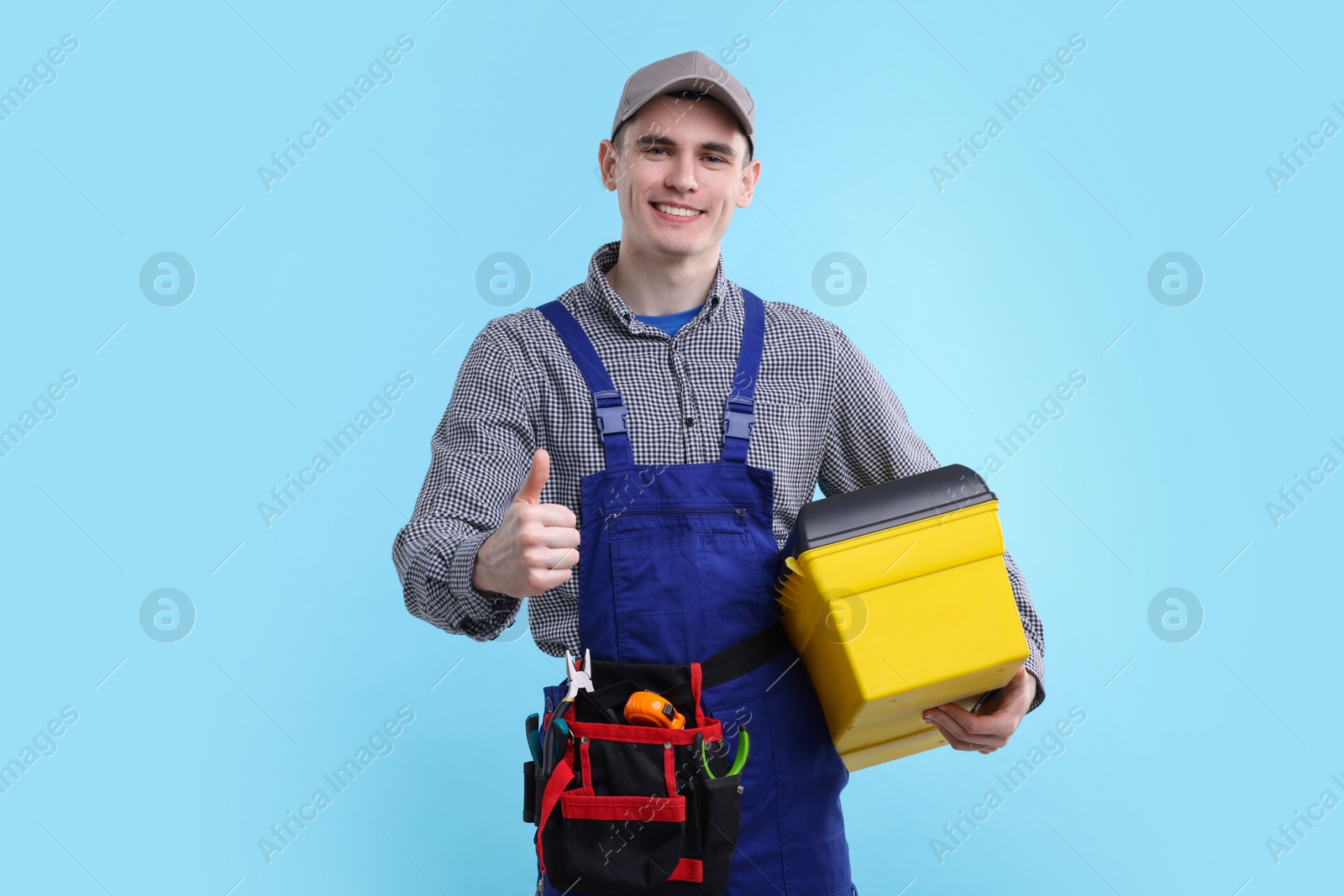 Photo of Professional repairman with tool box showing thumbs up on light blue background