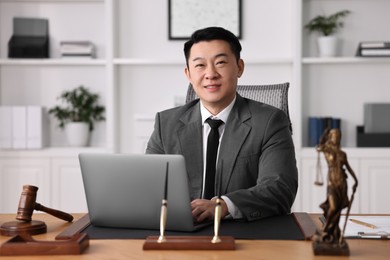 Photo of Happy notary working with laptop at wooden table in office