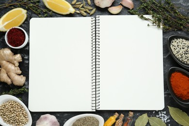 Photo of Blank recipe book surrounded by different ingredients on black textured table, flat lay. Space for text