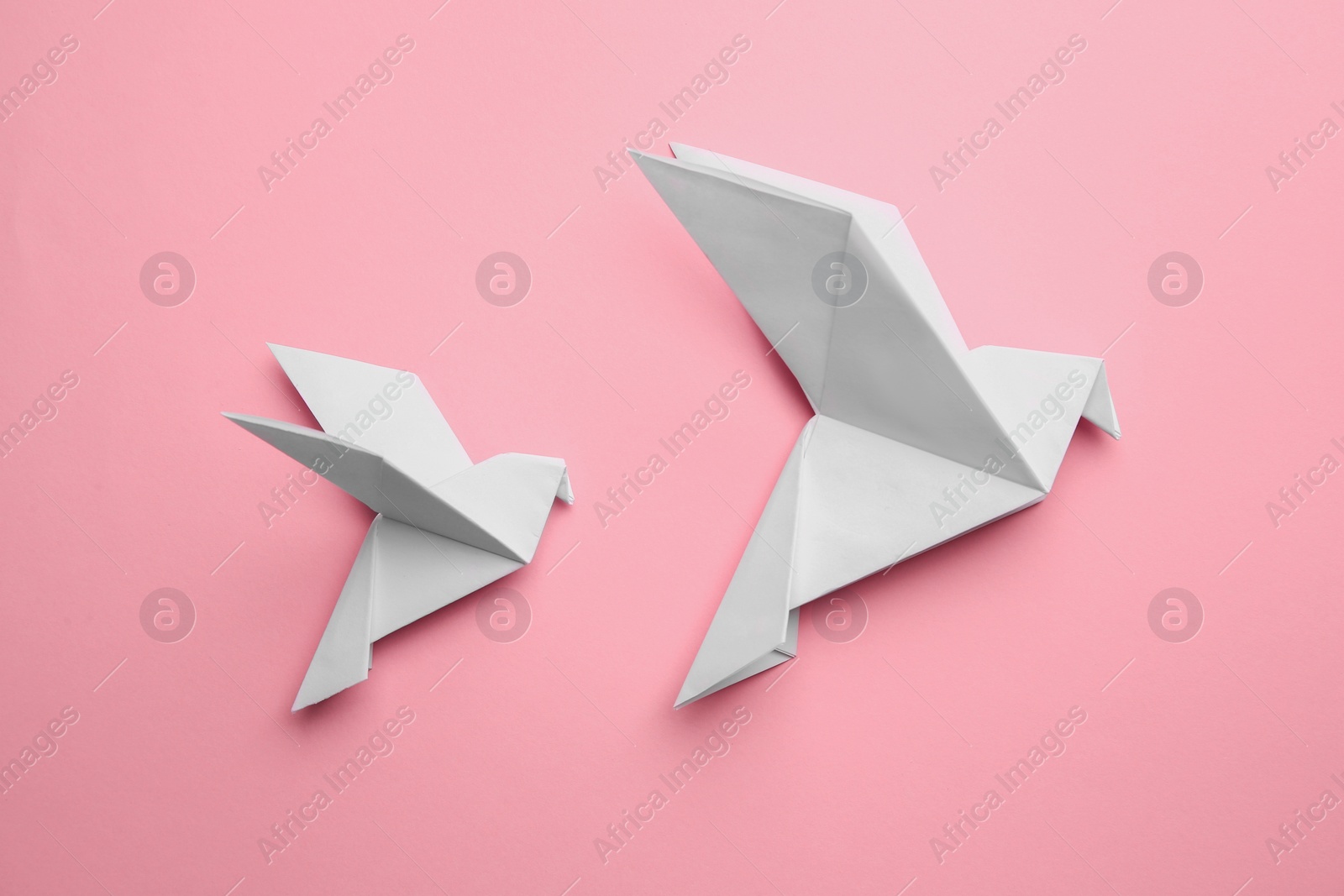 Photo of Beautiful origami birds on pink background, flat lay