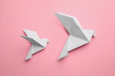 Photo of Beautiful origami birds on pink background, flat lay