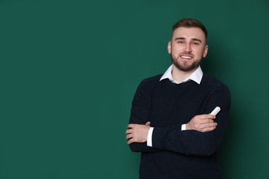 Portrait of young teacher with chalk on green background. Space for text