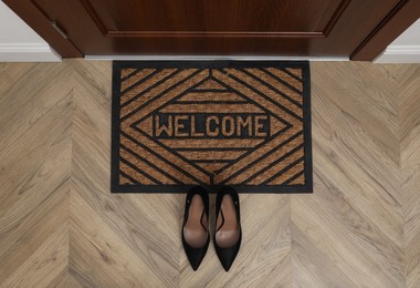 Photo of Stylish female shoes near door mat in hall, top view