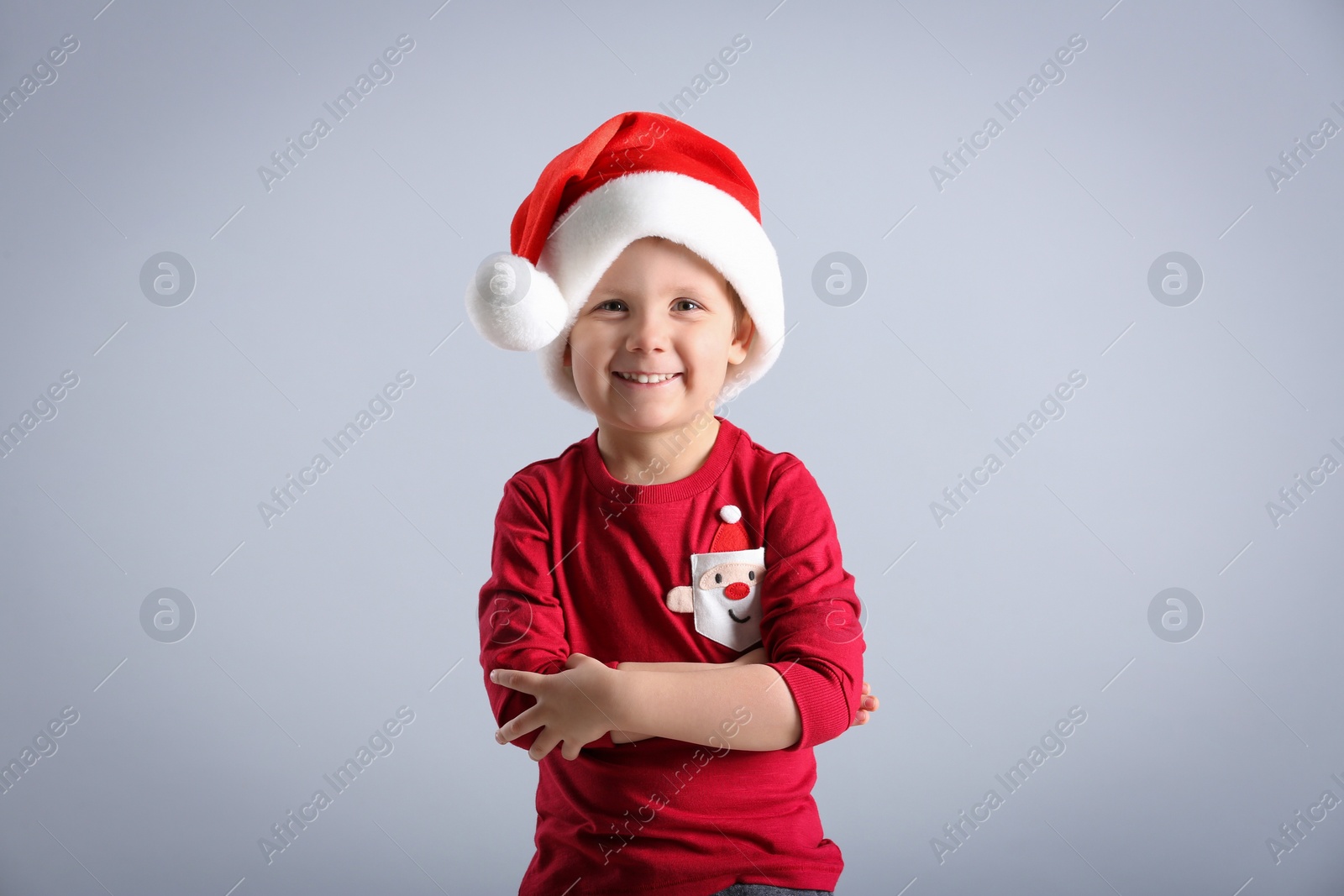 Photo of Cute little boy wearing Santa Claus hat on light grey background