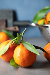 Tasty ripe tangerines with leaves on table