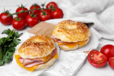 Photo of Delicious bagels with ham and cheese on white table