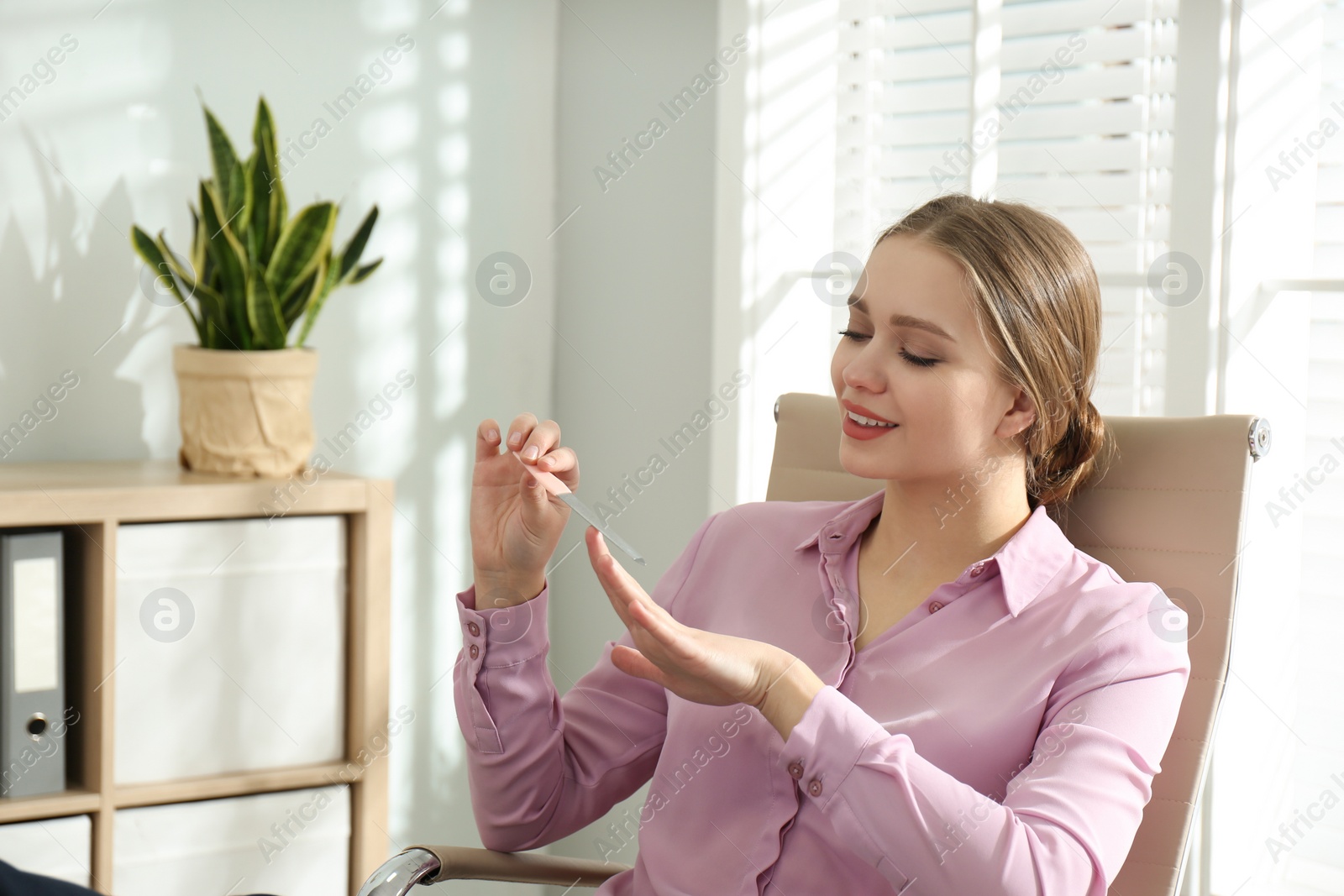 Photo of Lazy office worker doing her manicure indoors