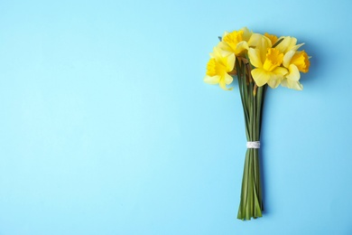 Photo of Bouquet of daffodils on color background, top view with space for text. Fresh spring flowers