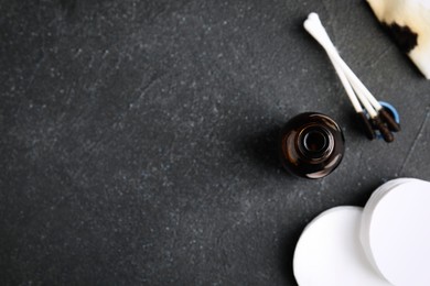 Photo of Bottle of medical iodine, cotton pads and buds on black table, flat lay. Space for text