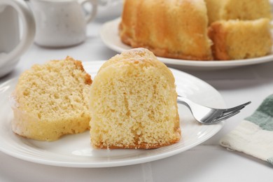 Photo of Pieces of delicious sponge cake and fork on white table, closeup