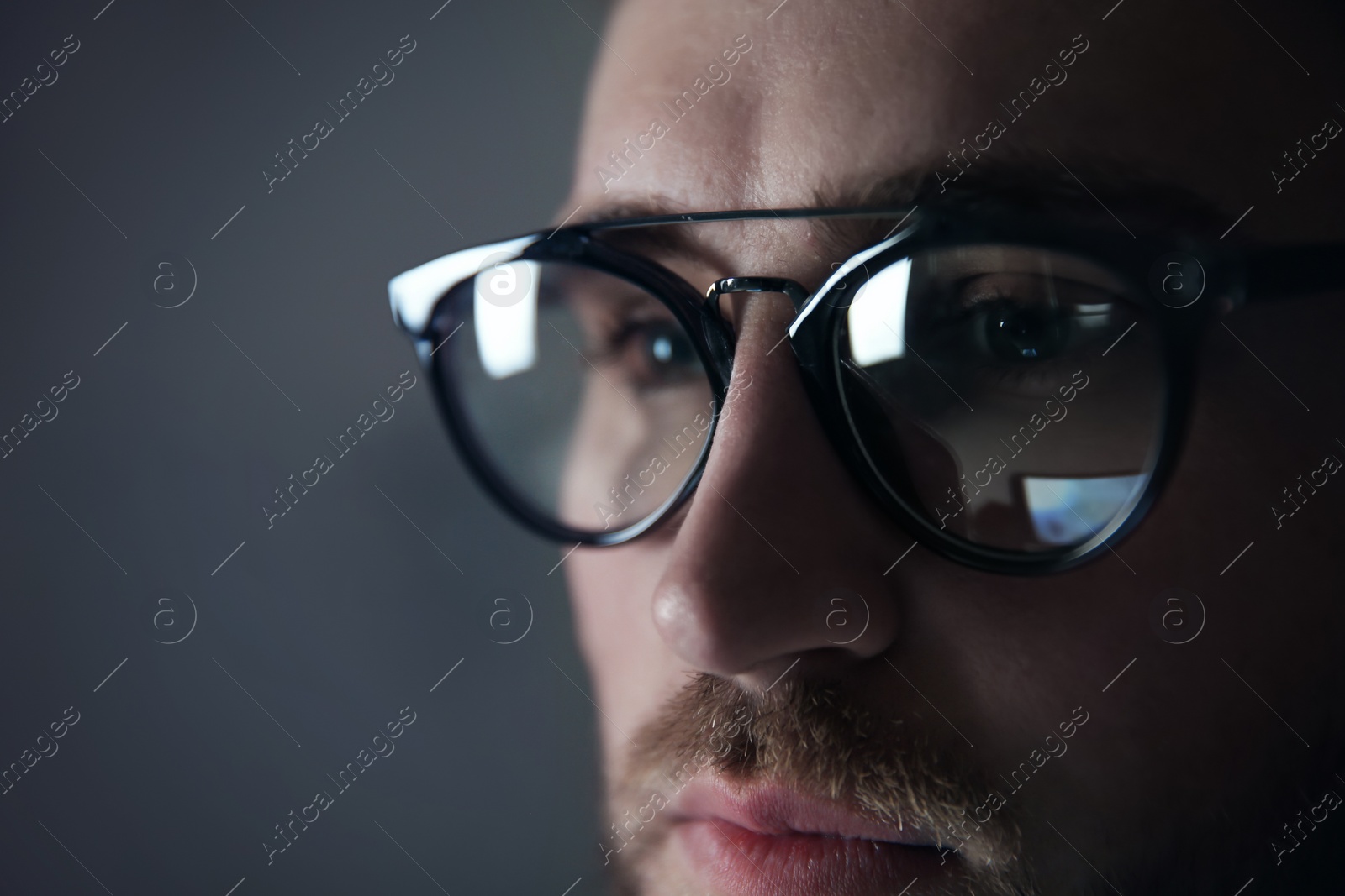 Photo of Young man wearing glasses on color background, closeup. Ophthalmology service