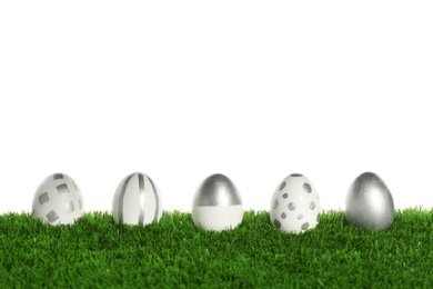 Line of painted Easter eggs on green lawn against white background