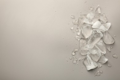 Photo of Pieces of crushed ice on grey background, top view. Space for text