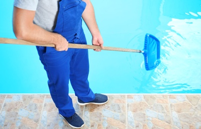 Photo of Male worker cleaning outdoor pool with scoop net