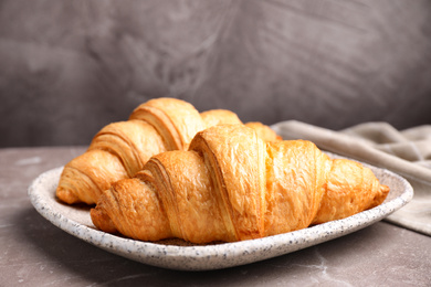 Tasty fresh croissants on brown marble table, closeup