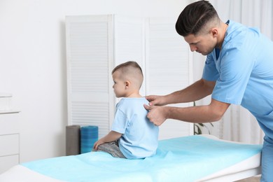 Photo of Orthopedist examining child's back in clinic. Scoliosis treatment