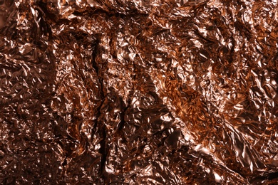 Photo of Crumpled rose gold foil as background, closeup view