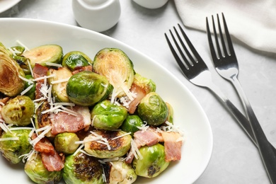 Photo of Delicious Brussels sprouts with bacon served on light table