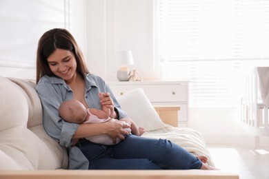 Photo of Young woman breastfeeding her little baby at home, space for text