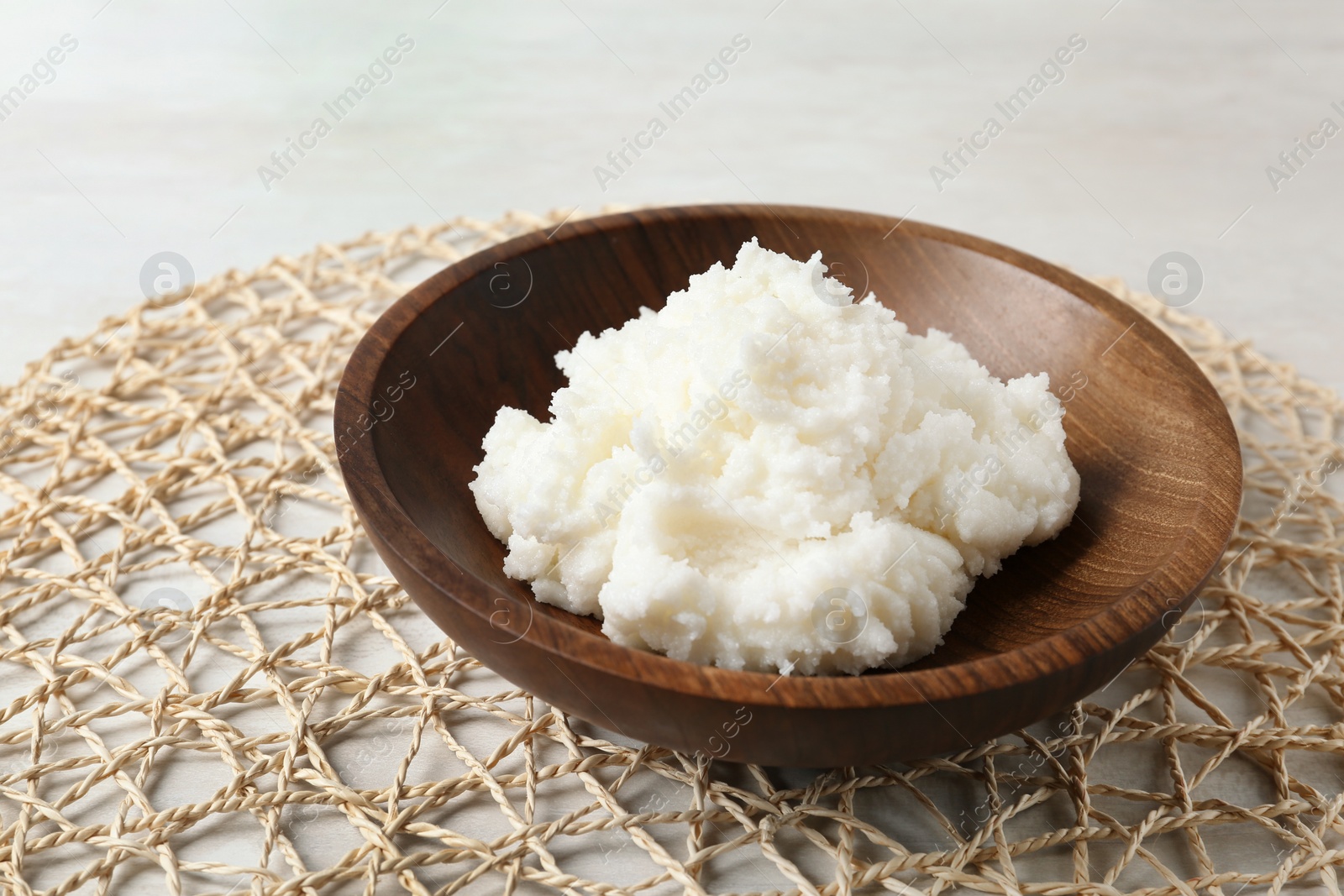 Photo of Shea butter in wooden bowl on table, closeup