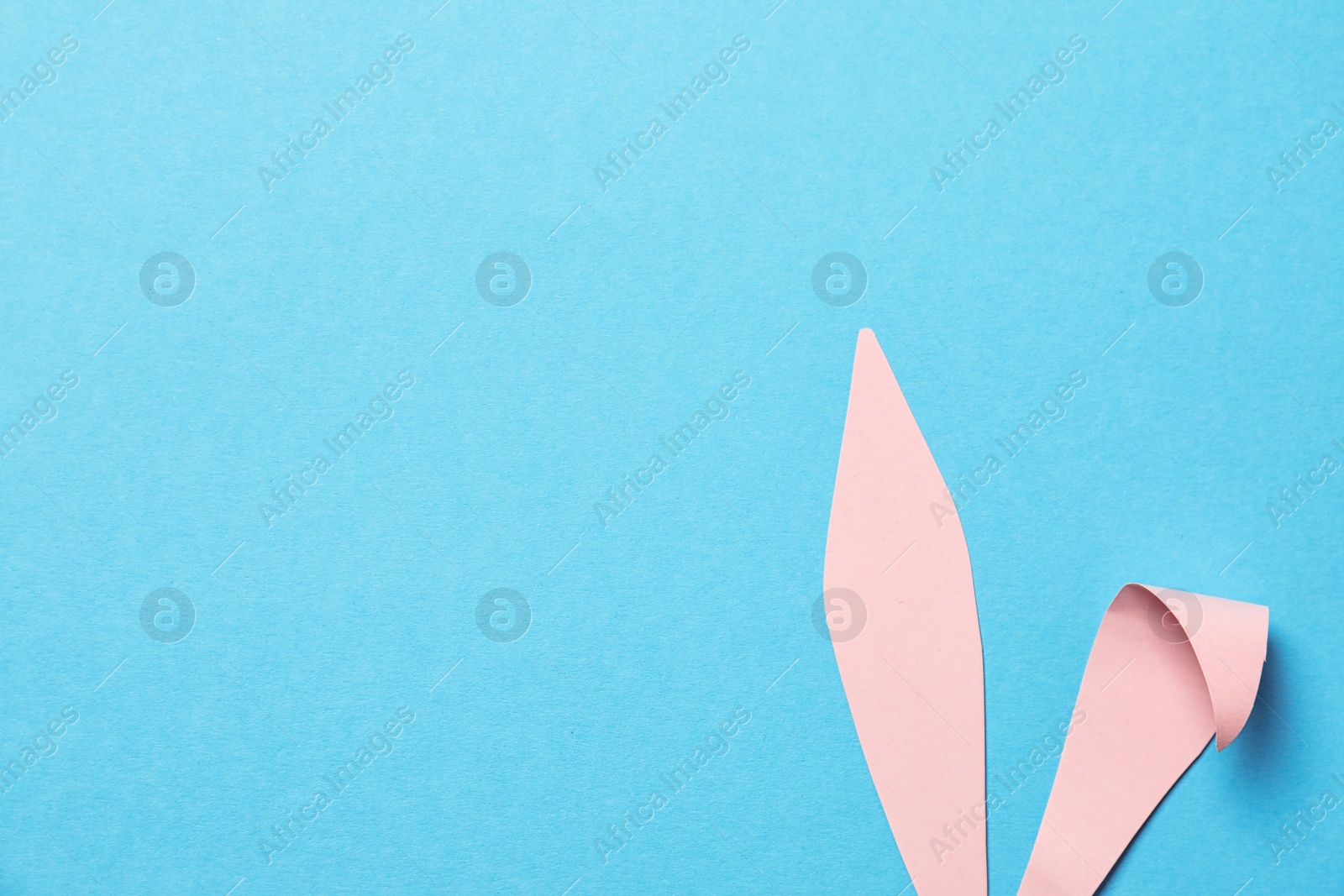 Photo of Funny Easter bunny ears on color background, top view with space for text