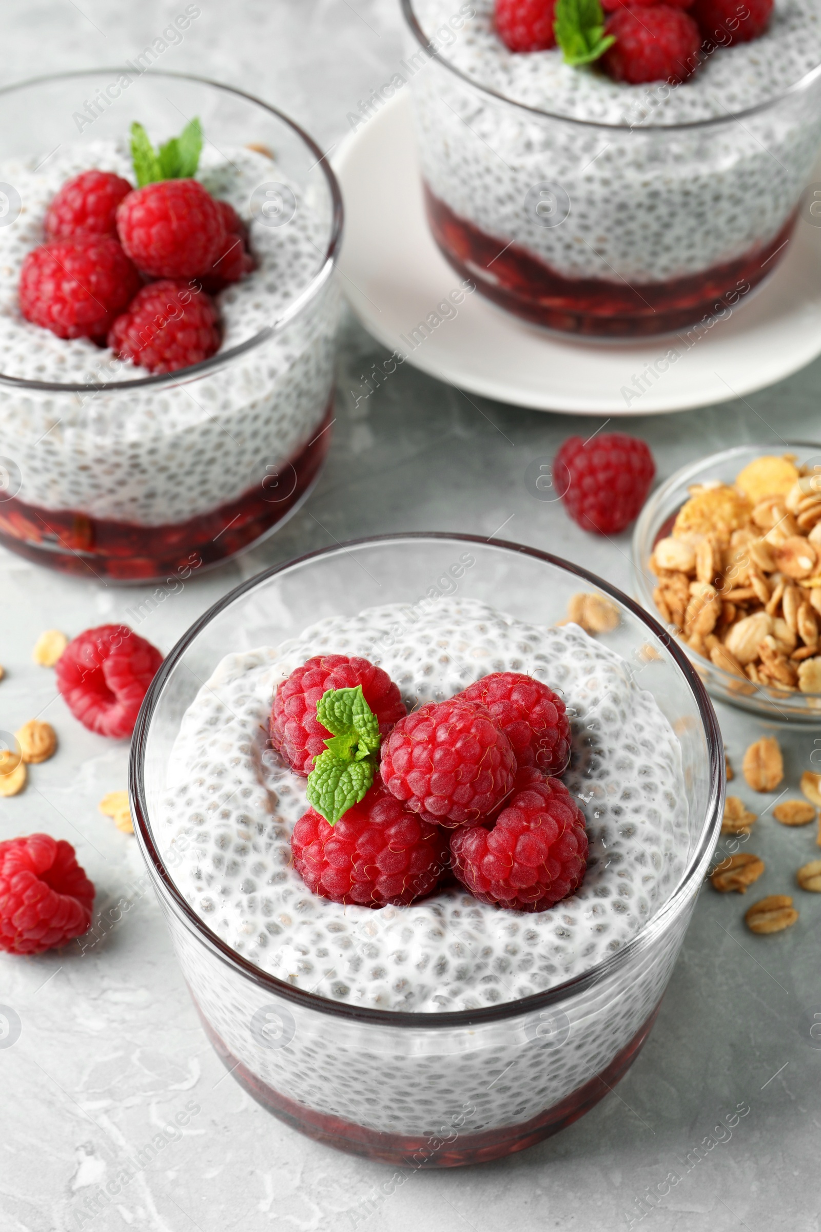 Photo of Delicious chia pudding with raspberries and mint on light marble table, above view