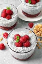 Photo of Delicious chia pudding with raspberries and mint on light marble table, above view