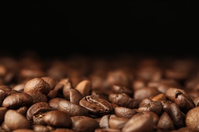 Many roasted coffee beans on black background, closeup. Space for text