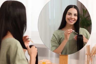 Beautiful woman applying hair serum in room. Cosmetic product