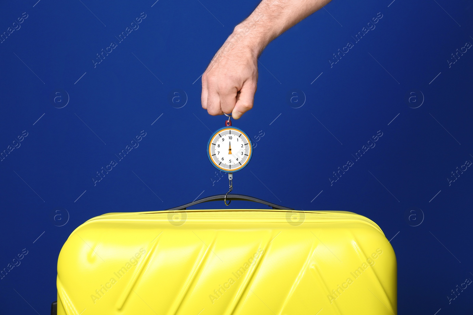 Photo of Man weighing stylish suitcase against color background, closeup