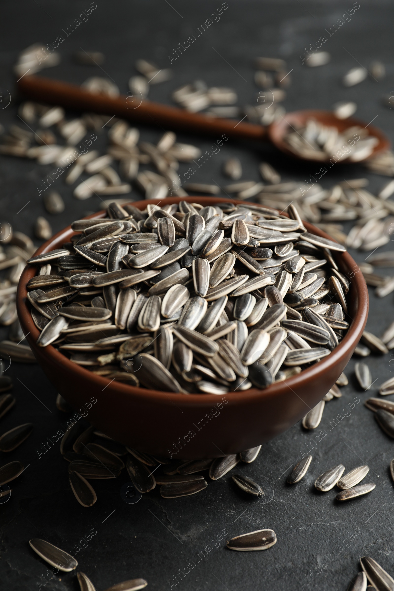 Photo of Organic sunflower seeds in bowl on grey table, closeup