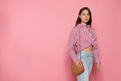 Photo of Beautiful young woman in fashionable outfit with stylish bag on pink background, space for text