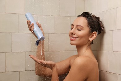 Photo of Happy woman pouring shampoo in shower at home. Washing hair