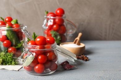 Pickling jars with fresh ripe vegetables on grey wooden table