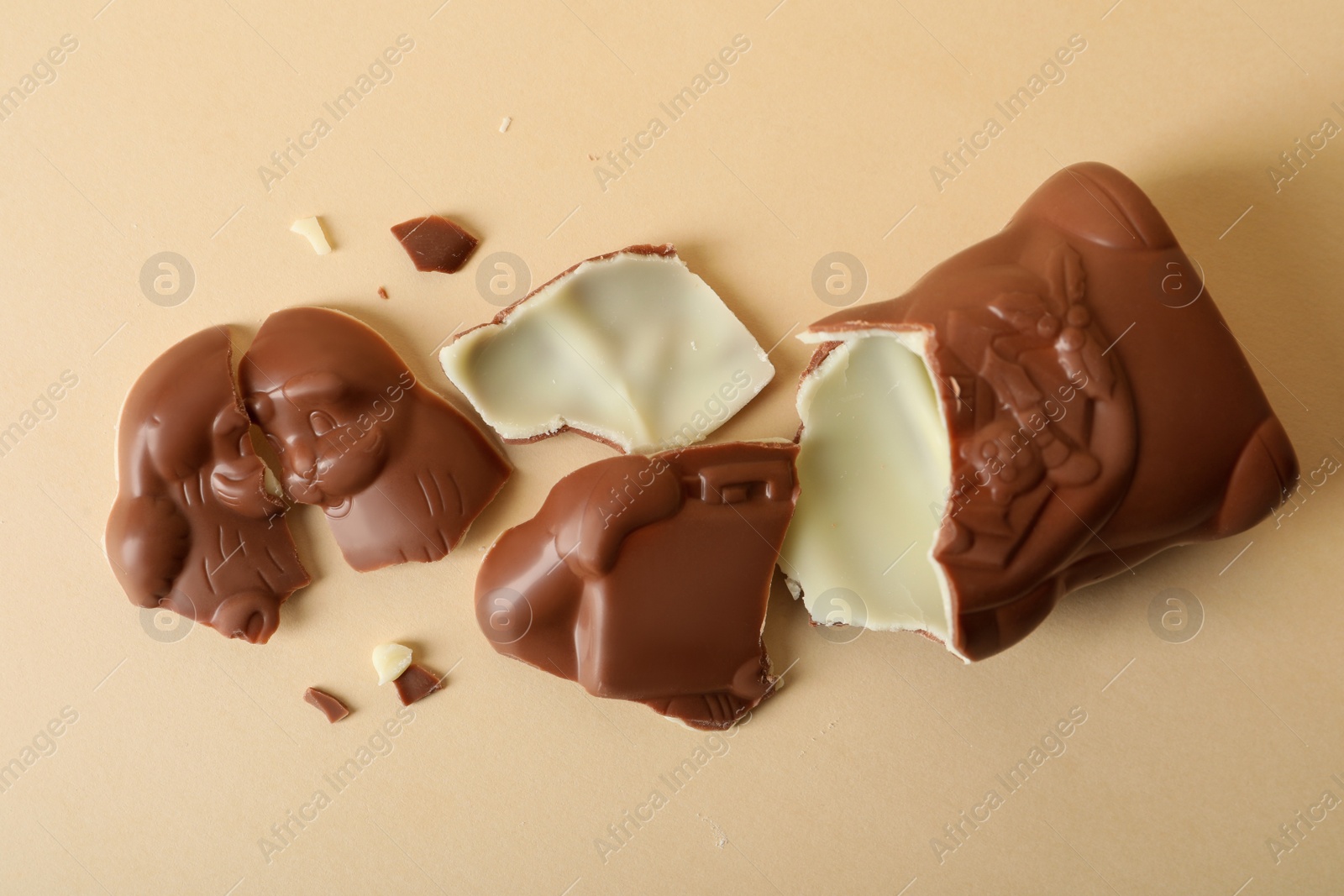 Photo of Broken chocolate Santa Claus on beige background, flat lay