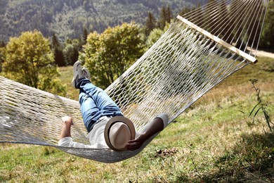 Photo of Young man resting in hammock outdoors on sunny day