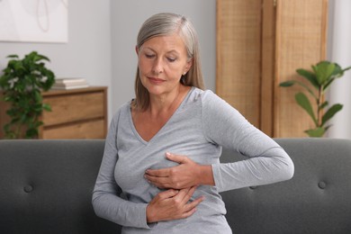 Photo of Beautiful senior woman doing breast self-examination at home