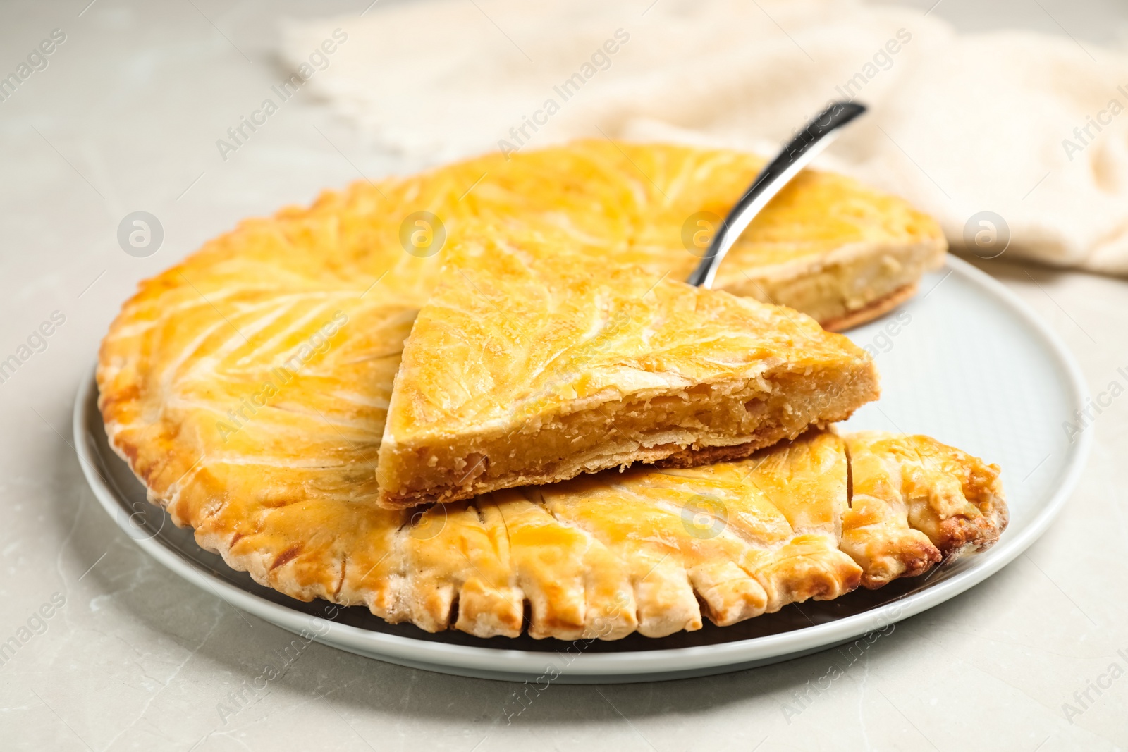 Photo of Traditional galette des rois on light grey marble table, closeup