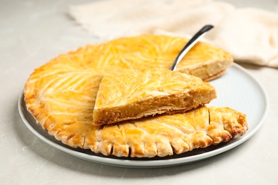 Photo of Traditional galette des rois on light grey marble table, closeup