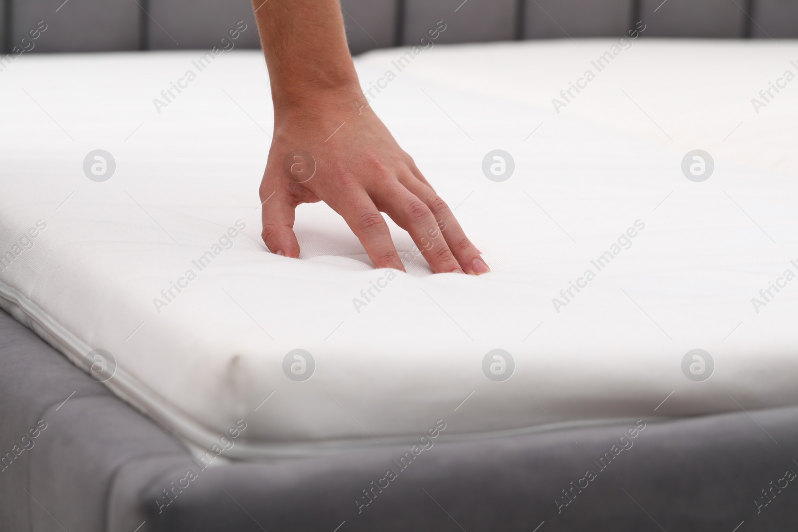 Photo of Man touching soft mattress indoors, closeup view