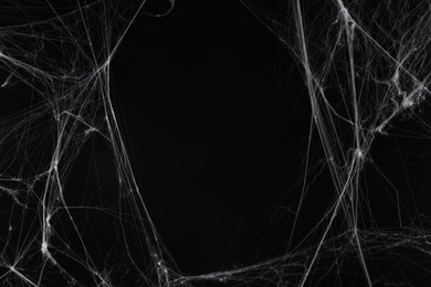 Photo of Creepy white cobweb on black background. space for text